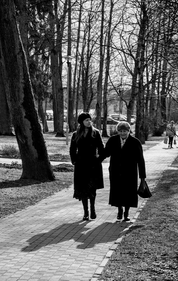 Two women hold hands walking through a park. Spending time with people and connecting with them is a healthy habit to foster empathy.