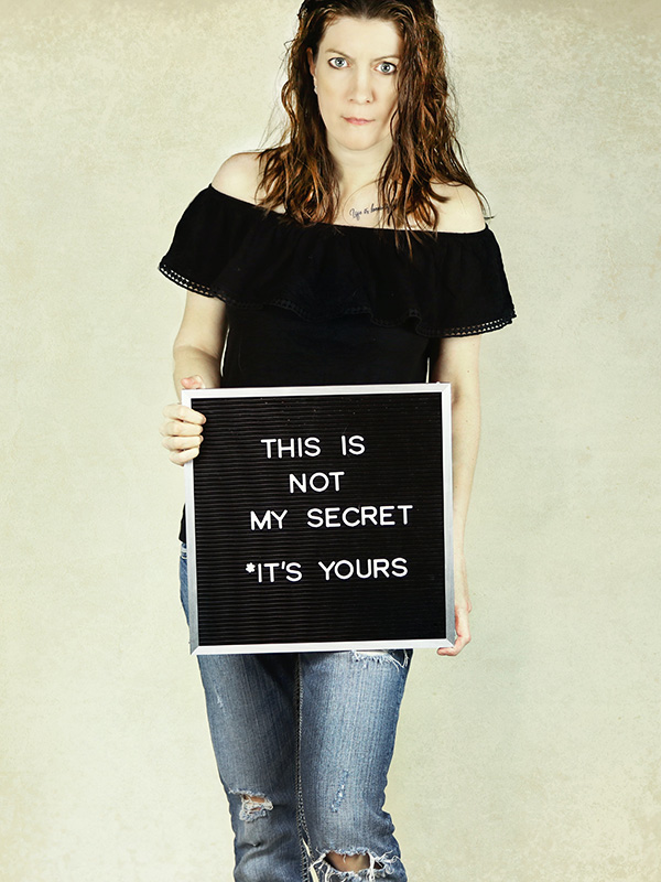 woman holding a sign that says this is not my secret it's yours