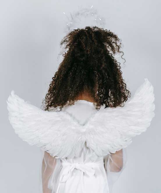 This girl has her back turned from the camera while she's wearing angel wings and a white dress. Girls are told at a young age to be good little angels.