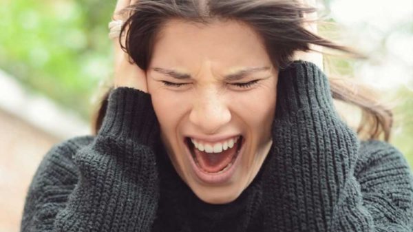 A woman screaming while holding her head