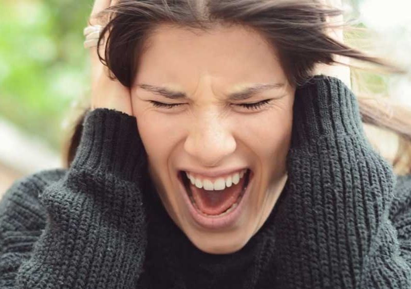 A woman screaming while holding her head